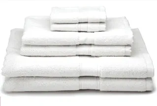 A neatly stacked set of white towels in various sizes, arranged from largest at the bottom to smallest at the top