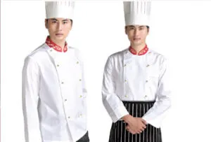 Two professional chefs wearing white double-breasted jackets with red collars, tall white chef hats, and one with a black-and-white striped apron.